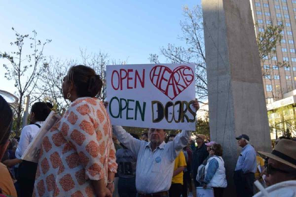 Manifestante con un cartel en inglés que dice_ corazones abiertos, puertas abeirtas
