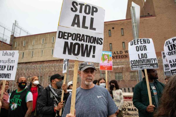Manifestante con un letrero que dice detengan todas las deportaciones ahora