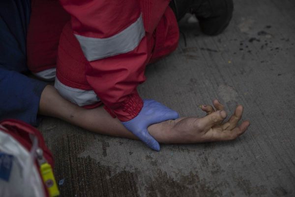 Paramédico sostiene la mano de hombre atendido por sobredosis