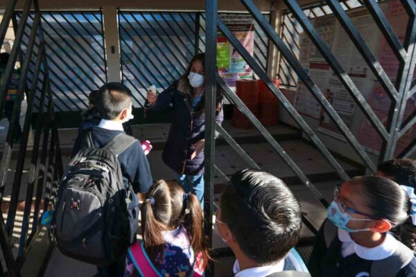 Maestra revisa temperatura de alumno ante casos de sarampión y uso obligatorio de cubrebocas en el estado de México 